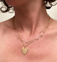 Gold necklace with a heart pendant on a person's neck
