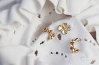 Gold earrings on a white lace fabric background